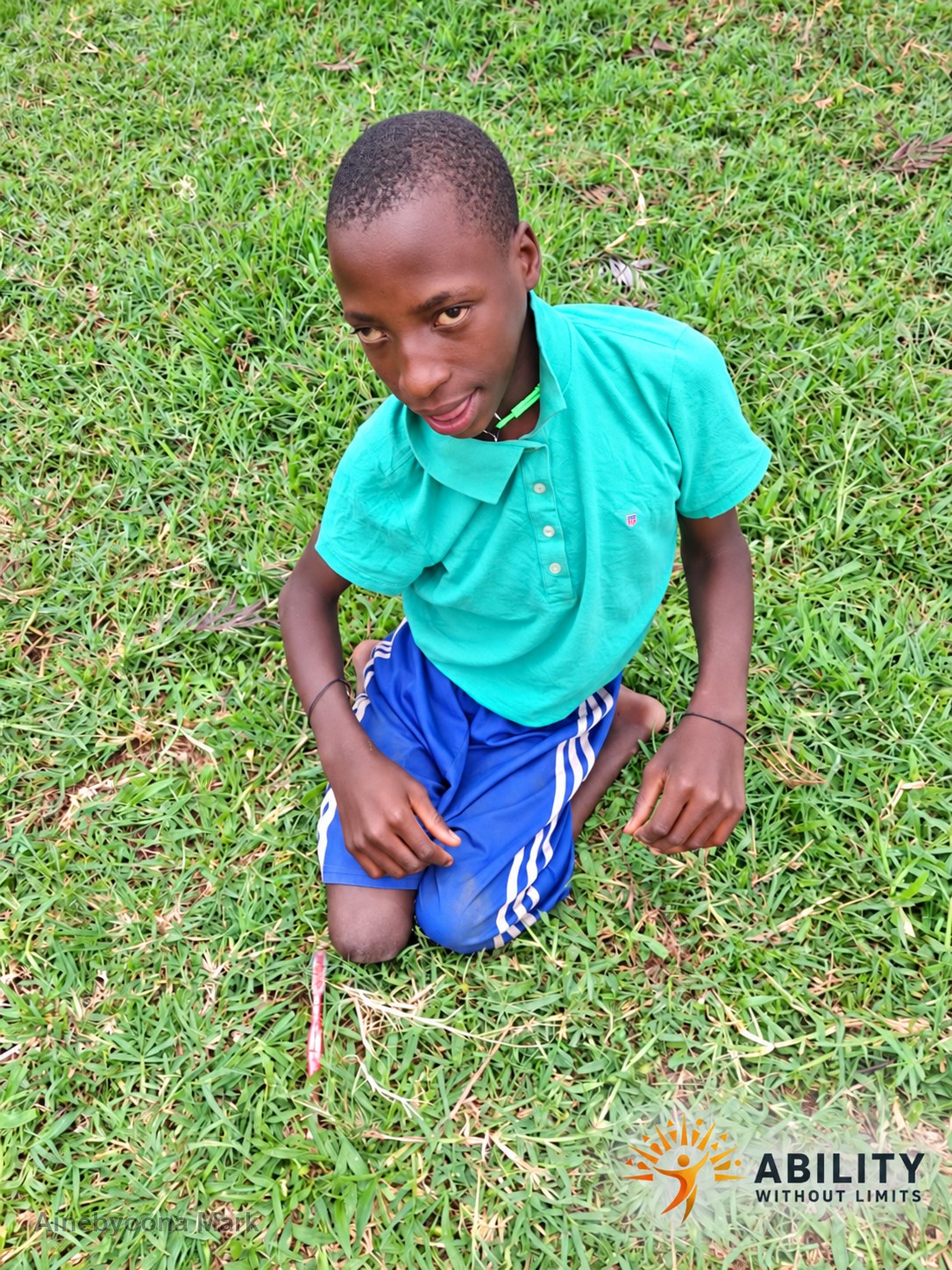 Ainebyoona Mark kneeling on grass outdoors