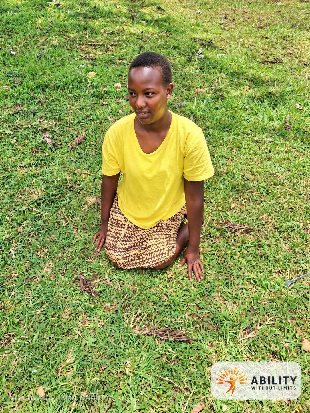 Amanyabyoona Daphine seated on grass outdoors